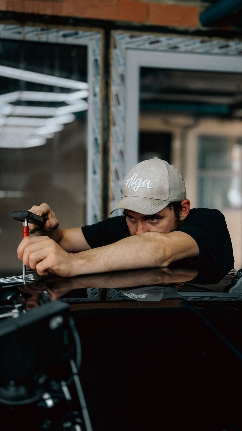 A technician working a dent with a rod
