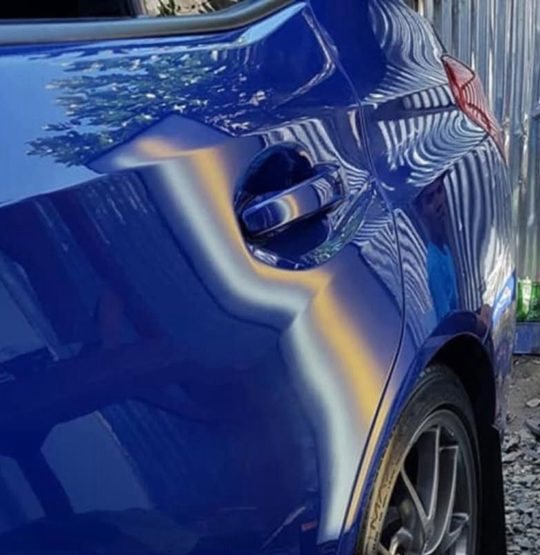 Blue door panel dent, after