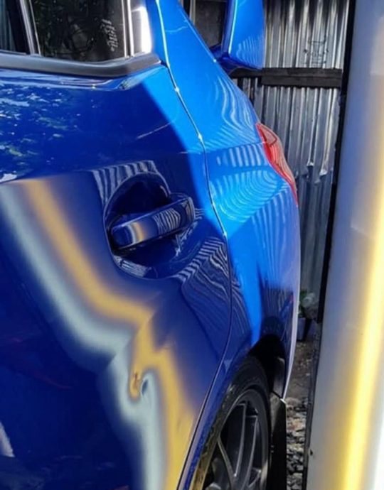 Blue door panel dent, before