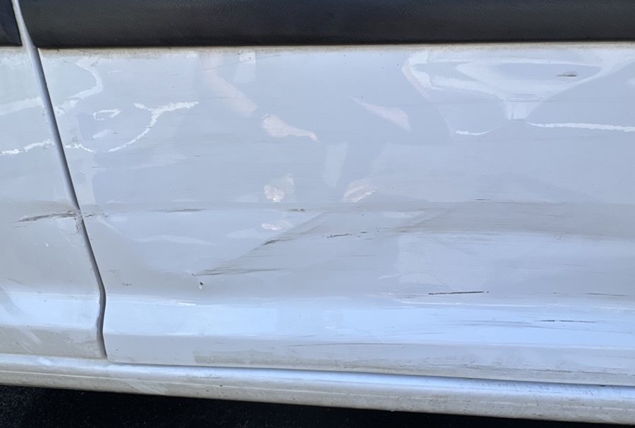 A white door with abrasions and scars across multiple panels
