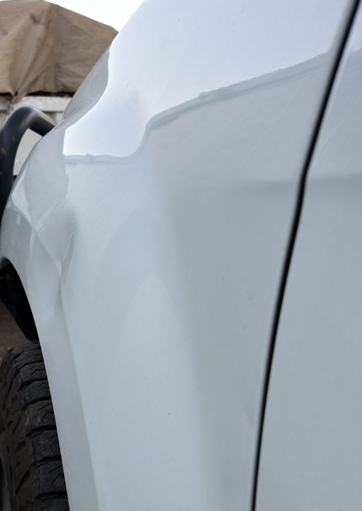 Side view of a sharp crease dent in a white guard
