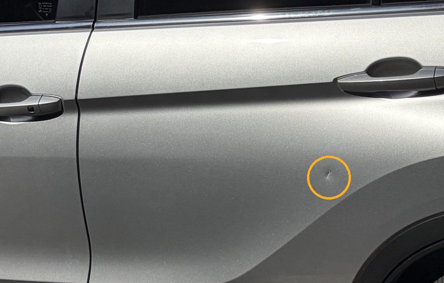 A small dent about the size of a 10 cent coin on a silver door